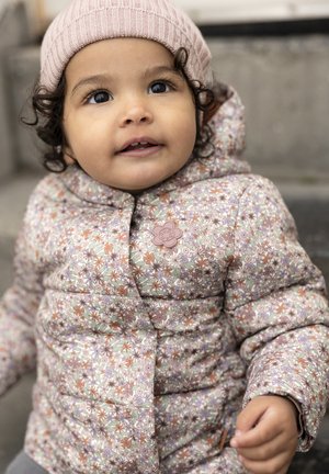 Veste rembourrée florale en rose pastel, ornée de motifs verts, orange et violets. Comprend un logo en forme de fleur décoratif. Bonnet en tricot rose.
