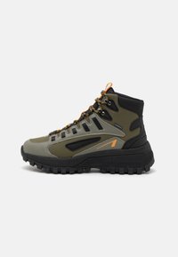 Mid-cut hiking shoe in olive green and black, featuring a rubber sole, textured upper, orange accents, and reinforced eyelets.