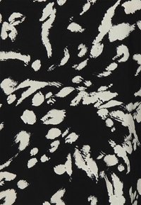 Svart tyg med ett abstrakt vitt penseldragsmönster, där olika former och storlekar på penseldragen skapar ett texturerat utseende.