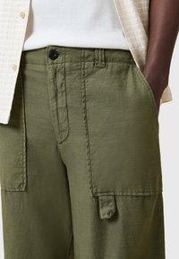 Pantaloni cargo verde oliva realizzati in tessuto testurizzato, con tasche laterali e chiusura anteriore con bottone. La vita è elasticizzata per garantire comfort.