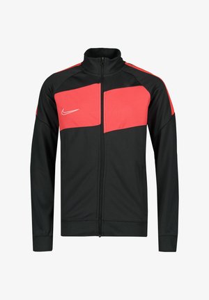 Zwarte sportjack met rode bovenpanelen, ritsvoorkant, hoge kraag en Nike-logo op de borst. Gemaakt van glad, lichtgewicht materiaal.