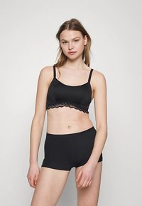 Bralette e boyshorts coordinati con rifiniture in pizzo nero. Materiale morbido con spalline regolabili. Design semplice e moderno che enfatizza il comfort.