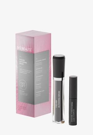 Pink and gray box labeled M2 Beauté Eyelash Activating Serum with two black serum bottles, one taller and one smaller, standing beside it.
