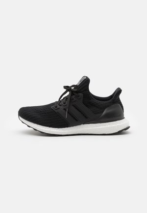 Black knit running shoe with white cushioned sole, lace-up design, and three black side stripes on a plain light gray background.
