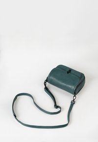Taschen aus teal Leder mit einem Reißverschluss, abgerundetem oberen Teil, abnehmbarem Riemen und schwarzen Hardware-Elementen. Glatte Textur, kompakte rechteckige Form.
