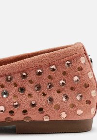 Zapato plano de ante rosa con punta redonda, adornado con cristales de diferentes tonalidades en un patrón disperso, con una suela de goma.
