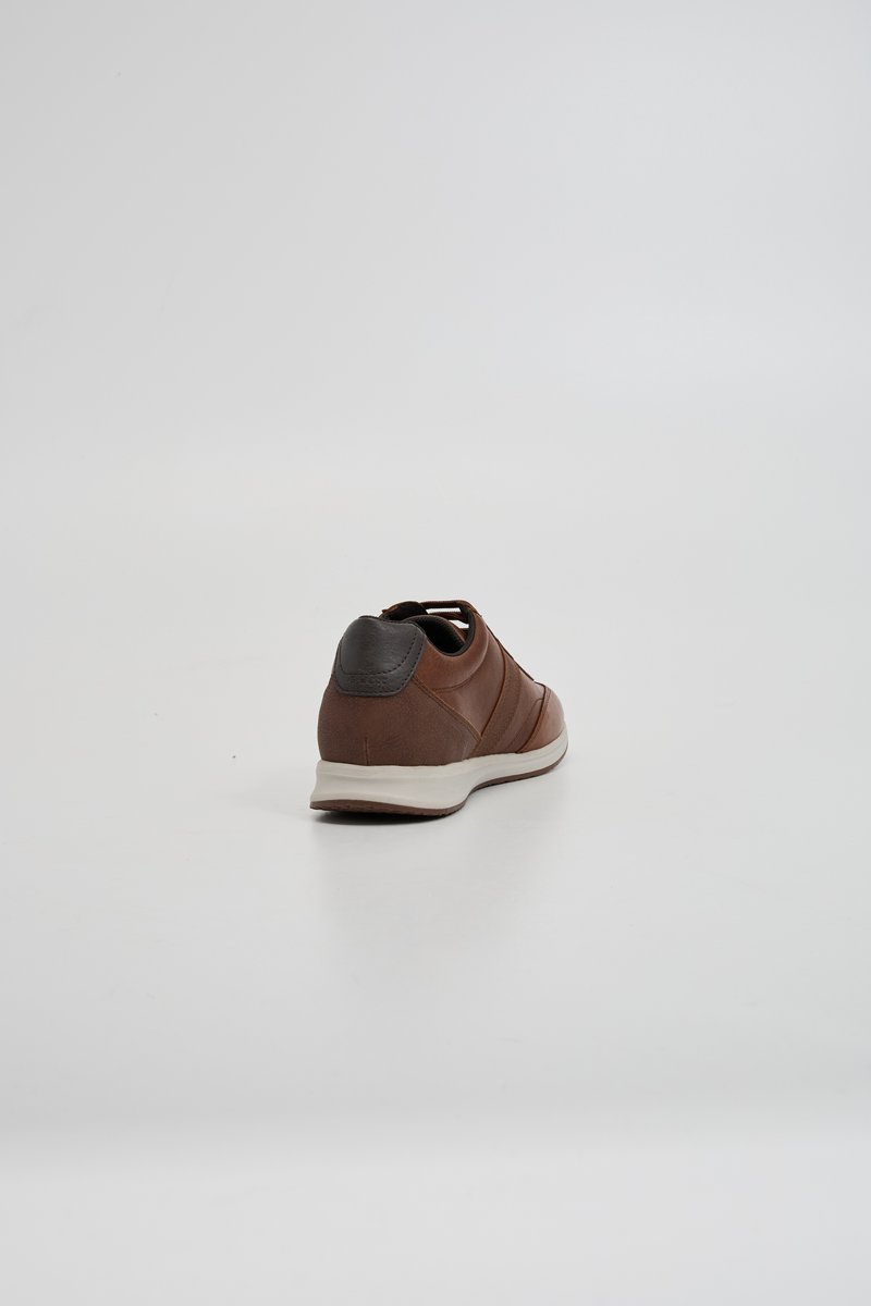 Sneaker in pelle marrone con tallone marrone scuro a contrasto, forma arrotondata, suola bianca e design minimalista.