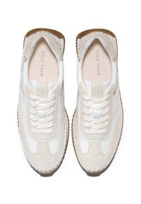 Vita och beige sneakers i läder och mocka, rund tå, vita snören och sula av gummigummi. "Cole Haan" tryckt inuti.