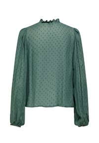 Σκούρο πράσινο μπλούζα με μακριά μανίκια, με υφή πουά, βολάν στον ψηλό λαιμό και μανσέτες με κουμπιά, εμφανίζεται από πίσω.