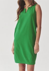 Green sleeveless dress with a V-neck, made of smooth fabric, featuring side slits and a relaxed fit, suitable for casual wear.