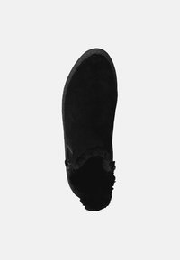 Bottes en daim noir avec un bout arrondi, doublure moelleuse et couture décorative à l'extérieur. La hauteur de la cheville est ornée d'une bordure douce, semblable à de la fourrure.