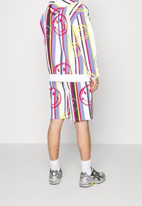 Gecombineerde hoodie en short in een kleurrijk gestreept patroon met glimlachende graphics. Gemaakt van lichtgewicht materiaal; heeft elastische manchetten en tailleband.