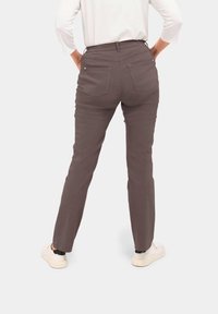 Pantalon gris avec une coupe droite, comportant deux poches arrière et une taille élastique. Porté avec des baskets blanches, vu de derrière.