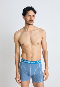Blue and pink striped boxer briefs with a wide blue waistband featuring "BJÖRN BORG" logo. Fabric appears smooth and elastic.