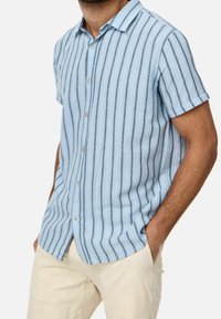 Camisa de manga corta en lino azul claro con rayas verticales azul oscuro, cierre frontal con botones y cuello clásico.