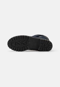 Semelle noire de chaussure de randonnée avec une bande de roulement robuste pour la traction, présentant un bord renforcé et une surface texturée, conçue pour la durabilité et l'adhérence.