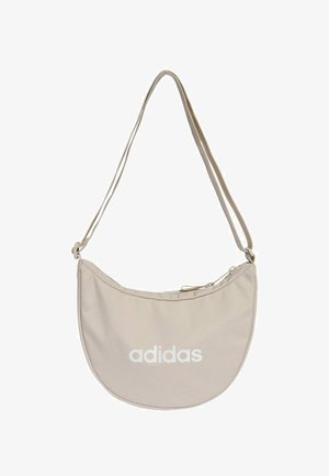 Beige fabric bag with a curved shape, adjustable strap, and a top zip closure. Features a large white "adidas" logo on the front.