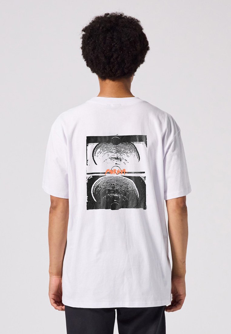 White cotton t-shirt featuring a graphic print on the back with concentric circular patterns in black and orange accents. Short sleeves.