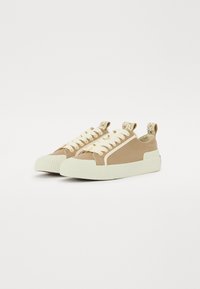 Baskets en toile beige avec des lacets crème, semelle en caoutchouc striée, languette à motif et panneau latéral contrastant pour plus de détails.