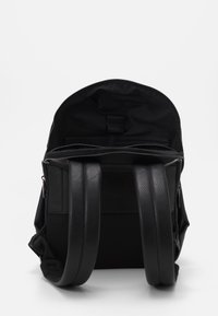 Black backpack with a smooth leather exterior, zippered top, and two padded straps. Interior features fabric lining and organizational pockets.