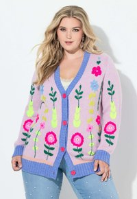 Pastelroze cardigan met levendige bloemrijke borduursels in roze, blauw en groen, met een blauwe V-halskraag en roze knopen.