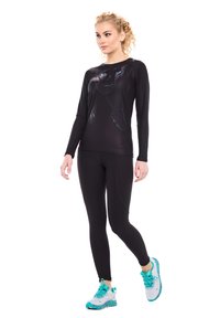Schwarzes, sportliches Langarmshirt mit Katzenmotiv, kombiniert mit schwarzen Leggings. Das Modell trägt Laufschuhe mit türkisen Akzenten.