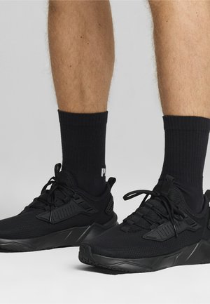 Chaussures de sport noires avec une tige en tissu texturé et des accents synthétiques. Elles disposent de lacets noirs, d'une semelle rembourrée et d'un profil en caoutchouc pour une bonne adhérence.