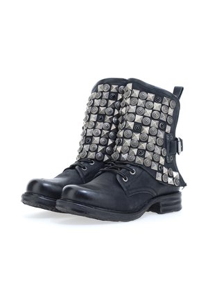 Zwarte leren enkellaarzen met platte hakken, voorzien van metalen studs in verschillende vormen op de bovenkant. Vetersluiting detail en een zijgesp accent.