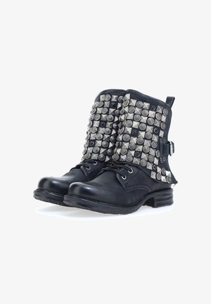 Zwarte leren enkellaarzen met platte hakken, voorzien van metalen studs in verschillende vormen op de bovenkant. Vetersluiting detail en een zijgesp accent.