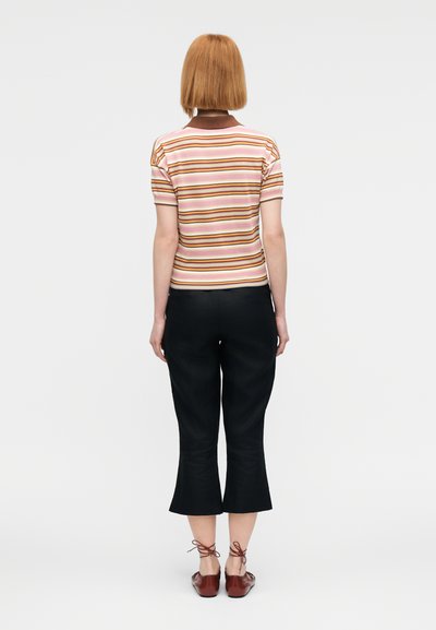 Ριγέ κοντομάνικο τοπ σε ροζ, πορτοκαλί και καφέ με καφέ γιακά, συνδυασμένο με μαύρο παντελόνι cropped και καφέ παπούτσια με κορδόνια.