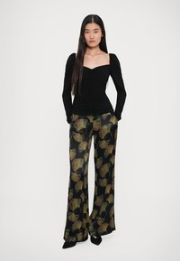 Top negru, ajustat, cu mâneci bufante, asortat cu pantaloni cu talie înaltă, având un model de frunze verzi și aurii, cu design drept.