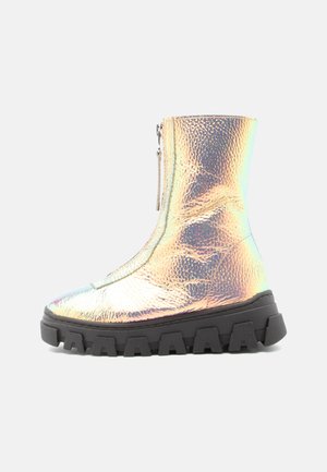 Botte de cheville holographique avec une finition brillante, un dessus texturé, une fermeture éclair sur le côté et une semelle en caoutchouc noir épaisse. Le design est élégant et moderne.