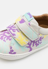 Leather shoe with a camouflage pattern in purple, yellow, and mint green. Features a velcro strap and a light-colored sole.