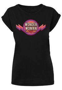 Svart T-skjorte med rund "Wonder Woman" grafikk. Designet har fet skrift i oransje, rosa og rødt med geometriske detaljer.
