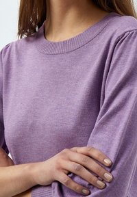 Ljuslila tröja med ribbad rund halsringning och lätt puffade ärmar, tillverkad av ett mjukt, texturerat tyg.