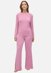 Top de manga larga rosa con detalles de encaje y pantalones de pierna acampanada a juego. Hecho de una tela suave y elástica con un ajuste cómodo.