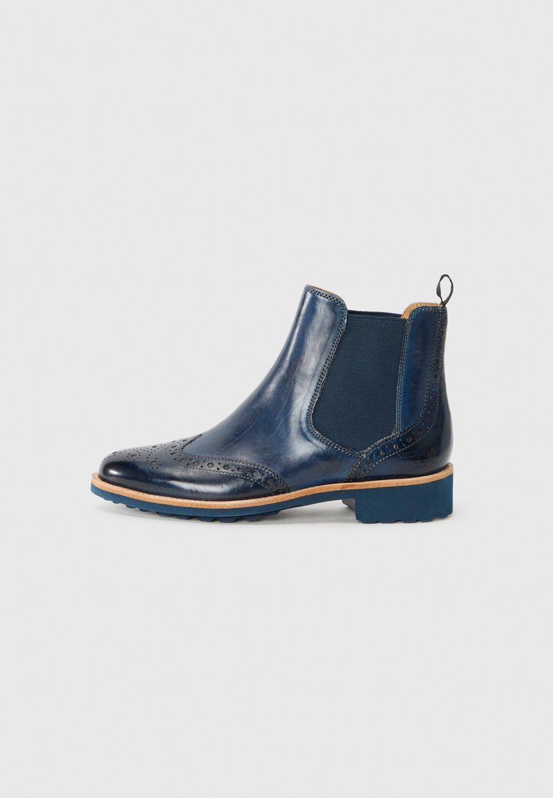 Bottines Chelsea en cuir marine avec des détails en brogue, panneaux latéraux élastiques et semelle en caoutchouc bleue. Présente un petit tirant à l'arrière.