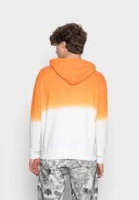 Hætte sweatshirt med en orange-til-hvid gradient, lavet af bomulds materiale, afslappet pasform, ribbede manchetter og kant, vist fra ryggen.