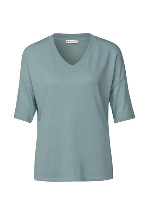 Helles teal-farbenes Kurzarmoberteil mit V-Ausschnitt. Weicher, strukturierter Stoff, lockere Passform und leicht heruntergesetzte Schultern. Markenlabel sichtbar.