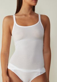 Witte mouwloze tanktop van een doorschijnende, elastische stof. Kenmerkt zich door dunne bandjes en een getailleerd ontwerp, met een soepele textuur.