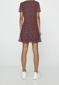 Robe à imprimé floral rouge et noir, manches courtes, corsage ajusté, jupe évasée, matériau semi-transparent, portée avec des baskets blanches.