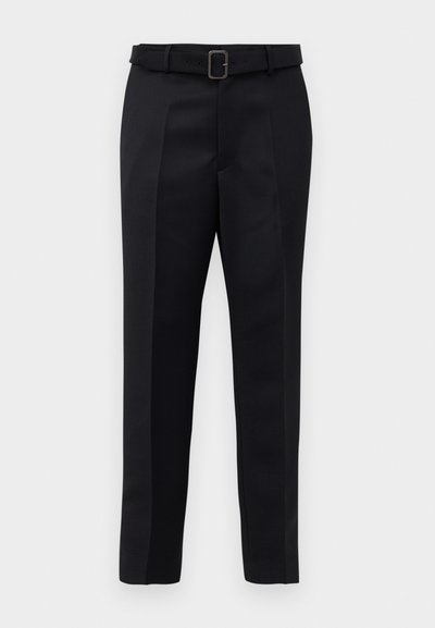 Melni piegriezti bikses ar gludu audumu, taisnu piegriezumu un jostu ar taisnleņķa sprādzi. Pamanāmie priekšējie iegriezumi uzlabo dizainu.