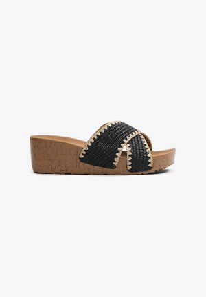 Sandalia deslizante negra de tejido con suela de corcho en cuña, que presenta acentos de costura en zigzag a lo largo de las correas y una plantilla suave en color beige.