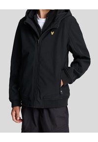 Veste softshell noire avec fermeture éclair à l'avant, capuche et poignets élastiques. Présente un petit logo jaune sur la poitrine et des poches latérales zippées.