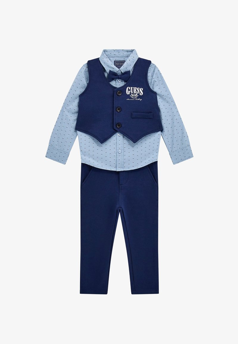 Jungenoutfit mit einem hellblauen, gemusterten Langarmhemd, einer dunkelblauen Weste mit Knöpfen und passenden Hosen. Enthält eine Fliege.