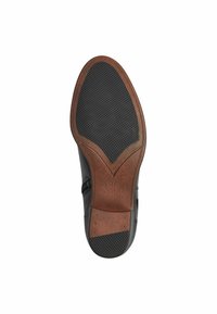 Suela de zapato negra con un agarre de goma texturizada y acentos de cuero marrón. Presenta una forma y tamaño distintivos con la marca "37".