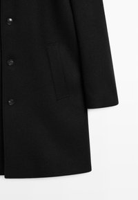 Black wool coat featuring a notched collar, long sleeves, five buttons, and a side pocket with a smooth texture. Plain design.