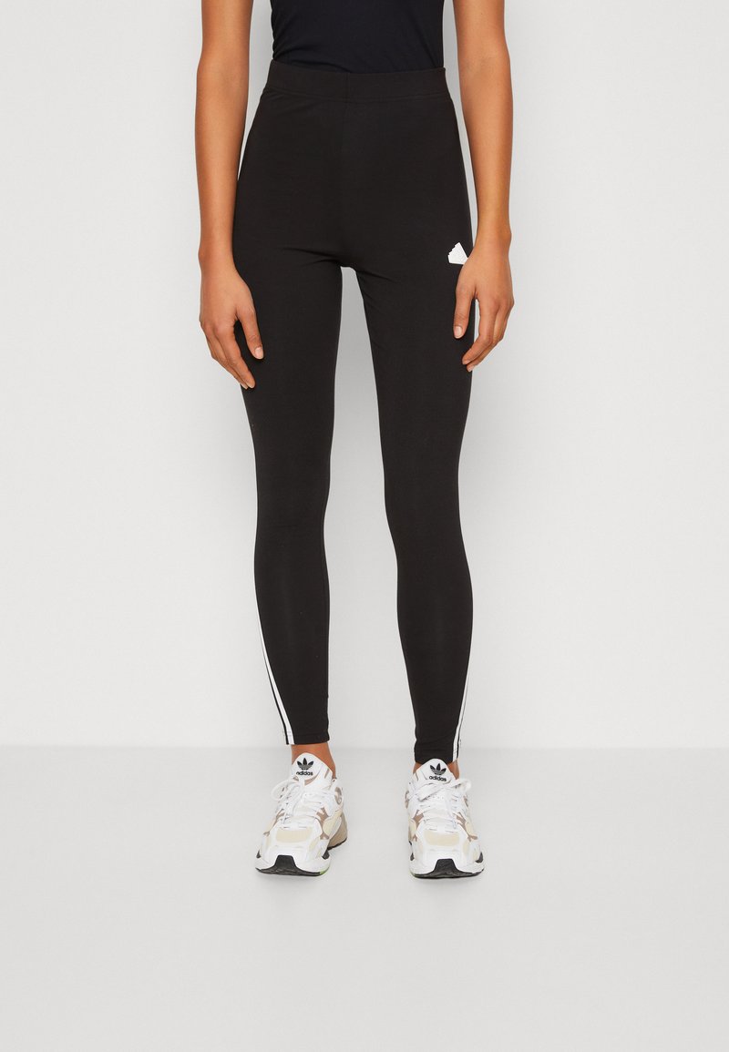 Leggings pretas com uma cintura alta, riscas brancas nas laterais e um pequeno logótipo branco na coxa; feitas de um tecido elástico para maior conforto.