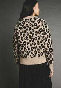 Leopardmuster-Pullover in Beige und Schwarz. Verfügt über einen gerippten Saum und Bündchen, hat eine lockere Passform und eine weiche Textur.