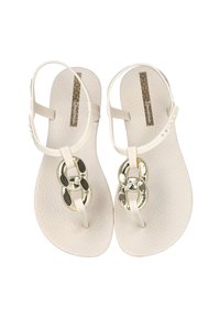 Sandalias planas blancas con suela texturizada y correa ajustable en el tobillo. Cuenta con detalles de cadena metálica en el dedo del pie.